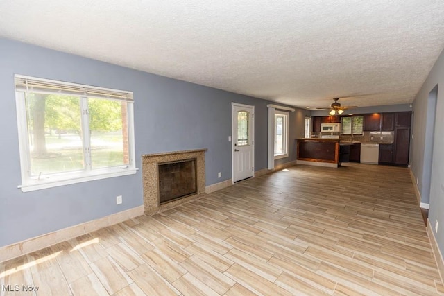 4011 Lancaster Rd, South Euclid, OH 44121 - unfurnished living room featuring healthy amount of natural light, light wood-style flooring, a textured ceiling, a premium fireplace, and a ceiling fan