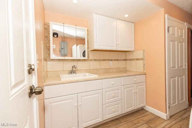4011 Lancaster Rd, South Euclid, OH 44121 - kitchen featuring washer / clothes dryer, white cabinetry, backsplash, light wood-type flooring, and recessed lighting