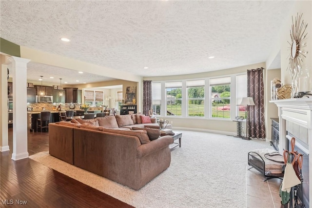 685 Shannon Pl, Aurora, OH 44202 - carpeted living room with recessed lighting, a textured ceiling, a fireplace, and decorative columns