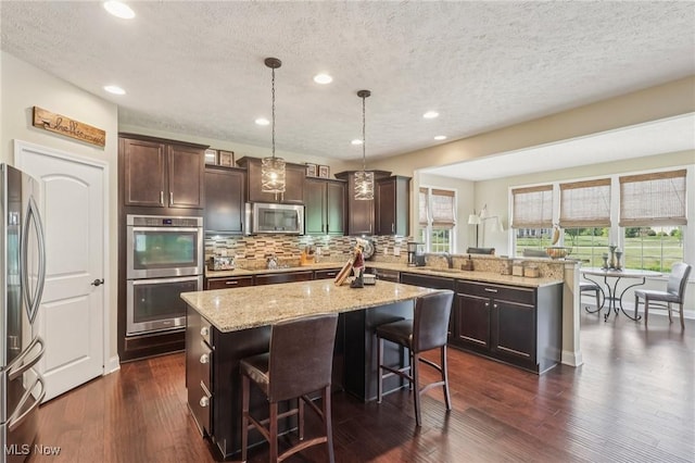 685 Shannon Pl, Aurora, OH 44202 - kitchen featuring stainless steel appliances, a peninsula, a textured ceiling, decorative backsplash, and light stone countertops