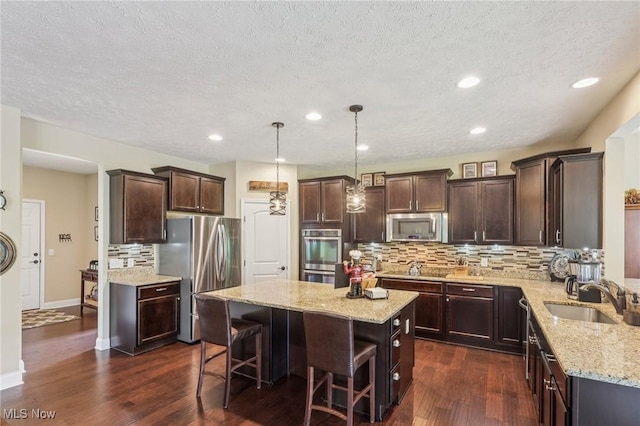 685 Shannon Pl, Aurora, OH 44202 - kitchen featuring appliances with stainless steel finishes, a kitchen island, light stone counters, backsplash, and dark wood-type flooring