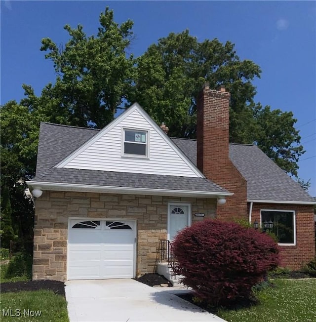 20171 Lake Shore Blvd, Euclid, OH 44123 - view of front facade with a shingled roof, stone siding, driveway, and a chimney