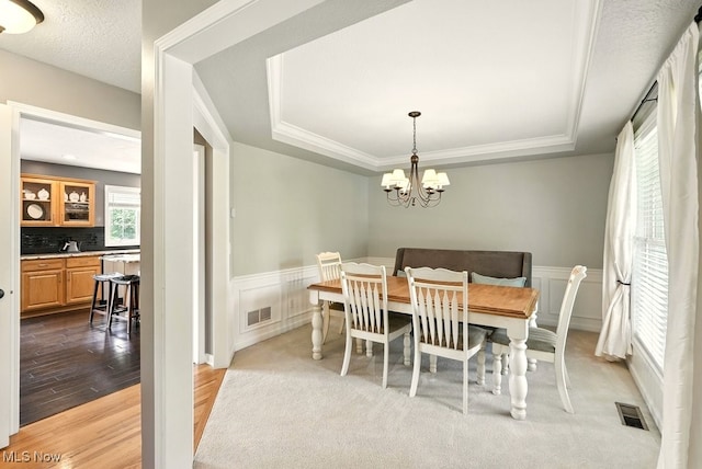 4020 Bishops Gate Cir, Stow, OH 44224 - dining space featuring a raised ceiling, wood finished floors, a chandelier, a wainscoted wall, and a decorative wall