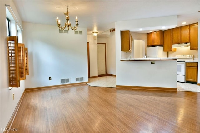 106 N Aspen Ct Unit 4, Warren, OH 44484 - kitchen featuring white appliances, under cabinet range hood, brown cabinetry, light wood-style flooring, and recessed lighting
