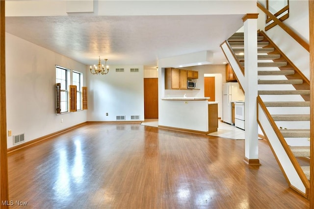 106 N Aspen Ct Unit 4, Warren, OH 44484 - unfurnished living room with wood finished floors, a chandelier, and stairs