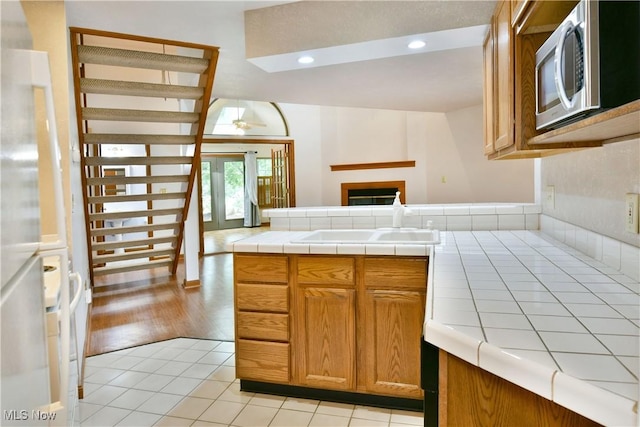 106 N Aspen Ct Unit 4, Warren, OH 44484 - kitchen featuring stainless steel microwave, tile countertops, a fireplace, light tile patterned floors, and brown cabinetry