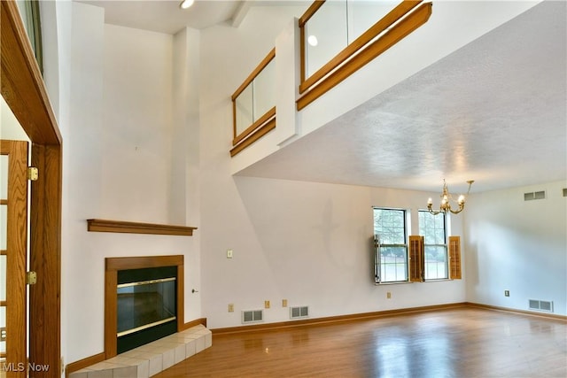 106 N Aspen Ct Unit 4, Warren, OH 44484 - unfurnished living room with wood finished floors, a chandelier, a tiled fireplace, and a towering ceiling