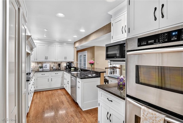 335 N Union Ave, Salem, OH 44460 - kitchen featuring stainless steel appliances, a peninsula, white cabinets, light wood-style flooring, and decorative backsplash
