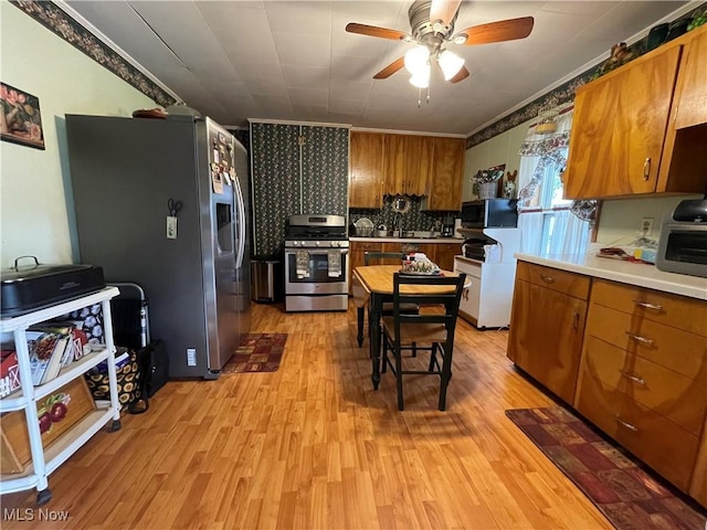 444 5th St NW, New Philadelphia, OH 44663 - kitchen with appliances with stainless steel finishes, light wood-style floors, brown cabinets, and crown molding