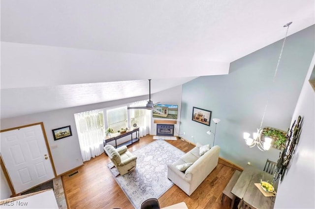 3310 Trappers Trl Unit C, Cortland, OH 44410 - living area featuring wood finished floors, vaulted ceiling, a fireplace, a ceiling fan, and a chandelier