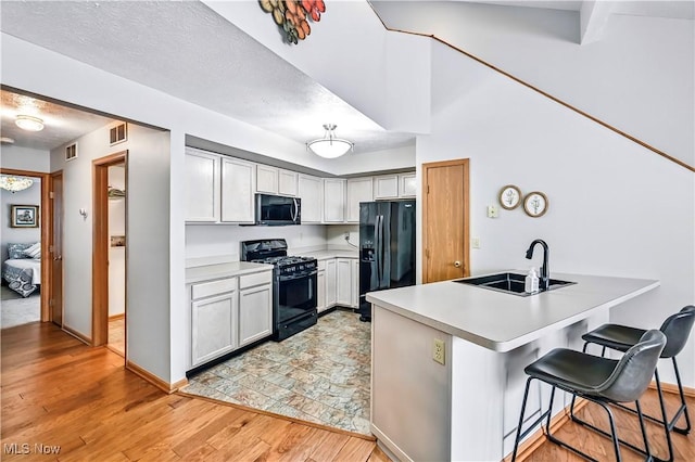 3310 Trappers Trl Unit C, Cortland, OH 44410 - kitchen featuring black appliances, a breakfast bar area, light countertops, and light wood finished floors