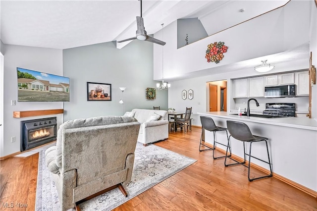 3310 Trappers Trl Unit C, Cortland, OH 44410 - living area featuring ceiling fan, a glass covered fireplace, light wood-style flooring, a chandelier, and high vaulted ceiling