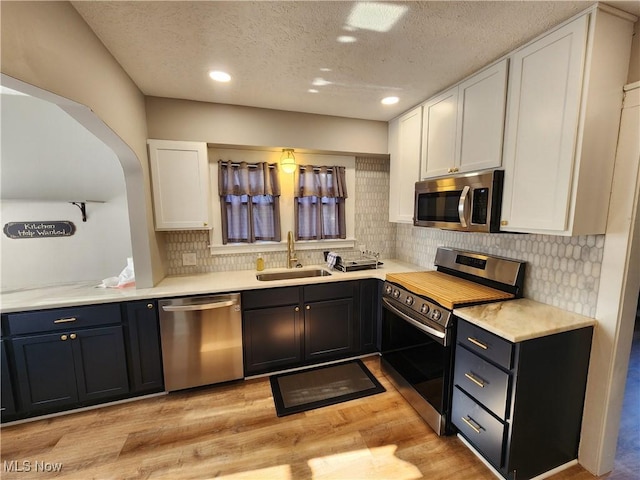343 Genesee Ave NE, Warren, OH 44483 - kitchen with stainless steel appliances, white cabinetry, a textured ceiling, light wood-style flooring, and backsplash