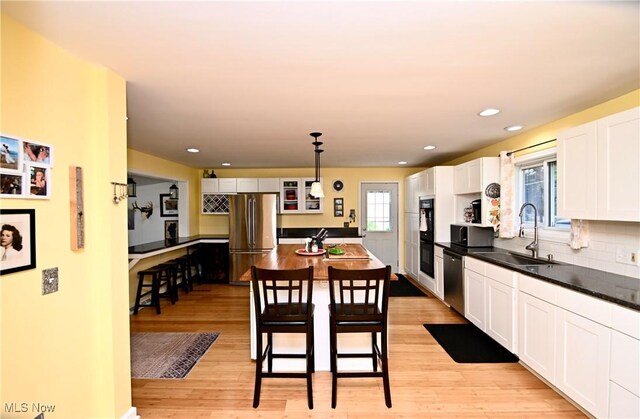 4219 3rd St NW, Canton, OH 44708 - kitchen with appliances with stainless steel finishes, light wood-type flooring, white cabinets, dark countertops, and decorative light fixtures