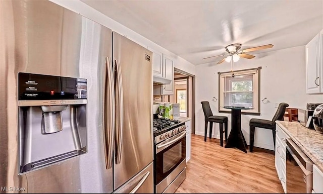 4611 W 158th St, Cleveland, OH 44135 - kitchen featuring appliances with stainless steel finishes, ceiling fan, white cabinetry, light wood-style floors, and under cabinet range hood