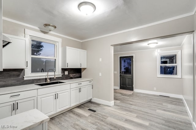 2819 4th St NW, Canton, OH 44708 - kitchen featuring decorative backsplash, white cabinets, light wood-style flooring, crown molding, and light stone counters