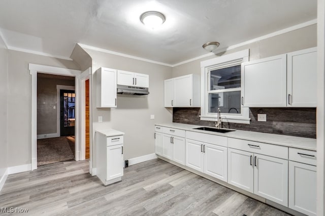 2819 4th St NW, Canton, OH 44708 - kitchen featuring under cabinet range hood, decorative backsplash, white cabinets, light wood-type flooring, and ornamental molding