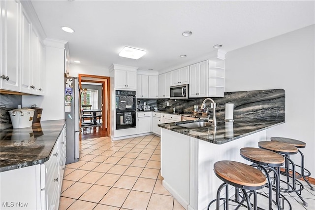 6388 Brianna Way NW, Warren, OH 44481 - kitchen featuring appliances with stainless steel finishes, a peninsula, tasteful backsplash, dark countertops, and recessed lighting