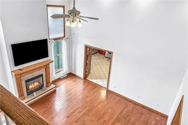 6388 Brianna Way NW, Warren, OH 44481 - unfurnished living room featuring wood finished floors, a ceiling fan, a glass covered fireplace, plenty of natural light, and a towering ceiling