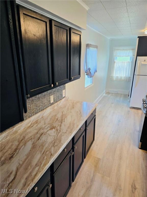 3986 Newton Falls Bailey Rd, Newton Falls, OH 44444 - kitchen featuring freestanding refrigerator, dark cabinetry, light wood-style floors, backsplash, and ornamental molding