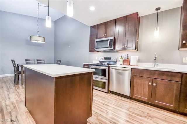 7208 S Galahad Pl, Concord Township, OH 44077 - kitchen featuring appliances with stainless steel finishes, light wood-style floors, a center island, light countertops, and decorative light fixtures