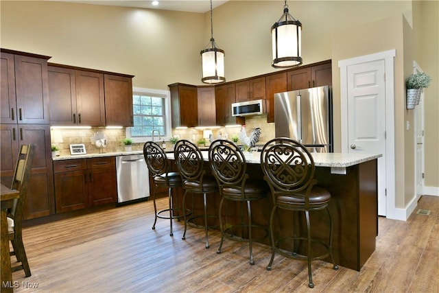 12 Bayview Cir, Cortland, OH 44410 - kitchen featuring stainless steel appliances, light wood finished floors, a breakfast bar, tasteful backsplash, and a kitchen island