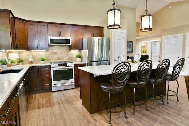 12 Bayview Cir, Cortland, OH 44410 - kitchen with appliances with stainless steel finishes, light wood finished floors, decorative backsplash, a center island, and high vaulted ceiling