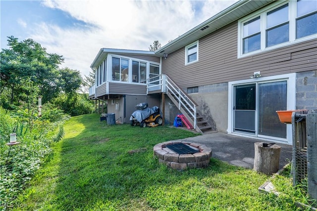 659 Lake Rd, Conneaut, OH 44030 - rear view of house with stairs, a fire pit, a sunroom, and a lawn