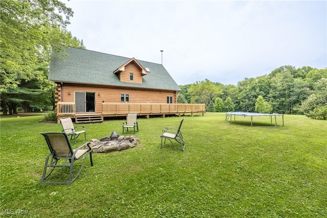 5621 Schustrich Rd, Mantua, OH 44255 - view of grassy yard featuring a trampoline, a fire pit, and a deck