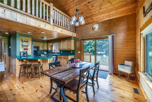 5621 Schustrich Rd, Mantua, OH 44255 - dining area with wood walls, light wood-style flooring, a chandelier, and a high ceiling