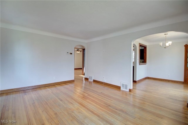 8102 Bertha Ave, Parma, OH 44129 - empty room featuring arched walkways, light wood-style floors, and a chandelier