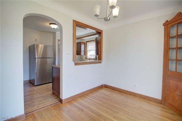 8102 Bertha Ave, Parma, OH 44129 - unfurnished dining area with light wood-style flooring, a chandelier, and arched walkways