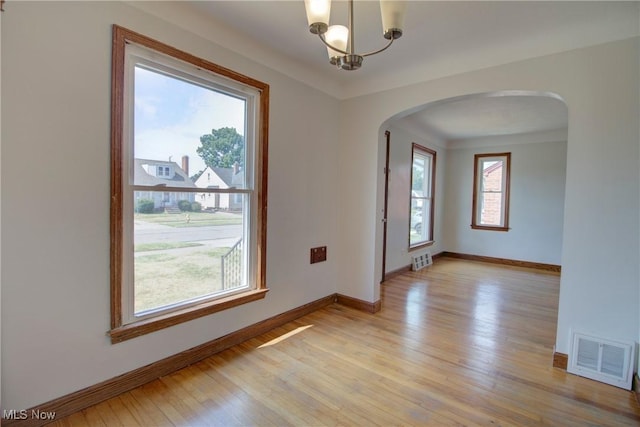 8102 Bertha Ave, Parma, OH 44129 - spare room with arched walkways, light wood-type flooring, and a chandelier