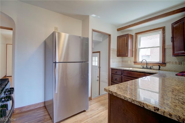8102 Bertha Ave, Parma, OH 44129 - kitchen with freestanding refrigerator, gas range oven, backsplash, light wood-style flooring, and light stone countertops