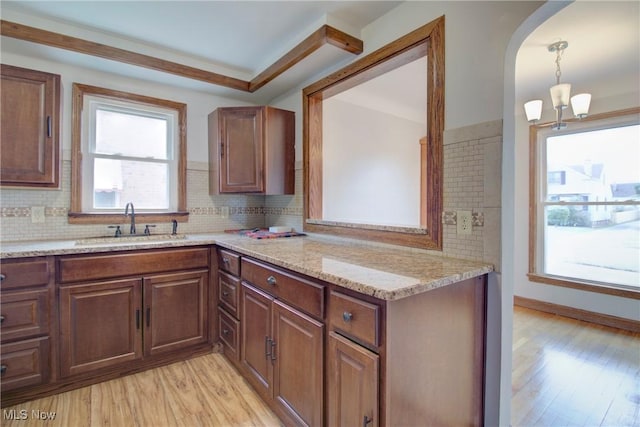 8102 Bertha Ave, Parma, OH 44129 - kitchen featuring light wood-style floors, backsplash, arched walkways, light stone counters, and decorative light fixtures