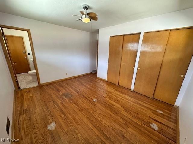 8375 Royal Ridge Dr, Parma, OH 44129 - unfurnished bedroom with two closets, wood finished floors, connected bathroom, and a ceiling fan