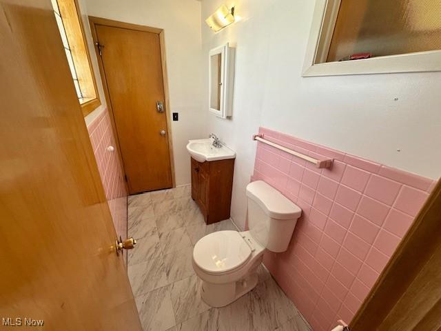 8375 Royal Ridge Dr, Parma, OH 44129 - bathroom with vanity, marble look tiles, tile walls, and a wainscoted wall