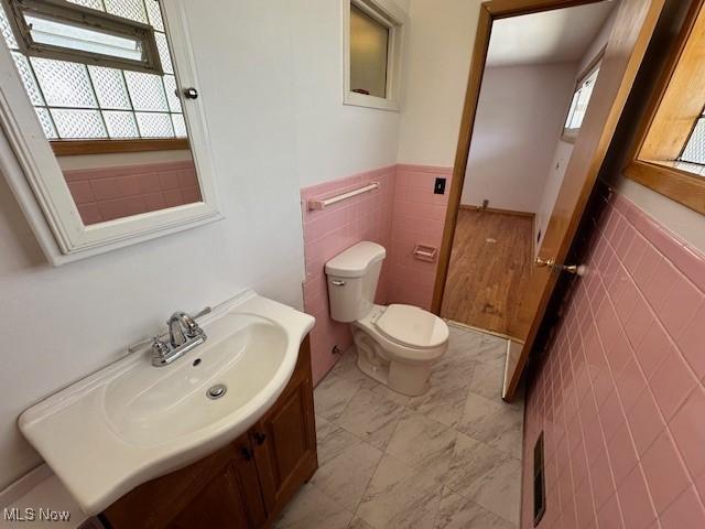 8375 Royal Ridge Dr, Parma, OH 44129 - half bath featuring tile walls, vanity, and wainscoting