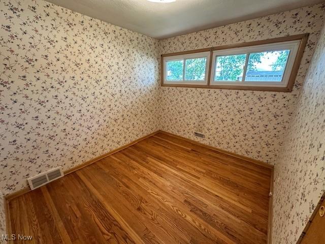 8375 Royal Ridge Dr, Parma, OH 44129 - spare room with wallpapered walls and wood finished floors