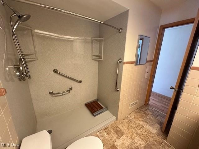 8375 Royal Ridge Dr, Parma, OH 44129 - bathroom with tile walls, a stall shower, and wainscoting