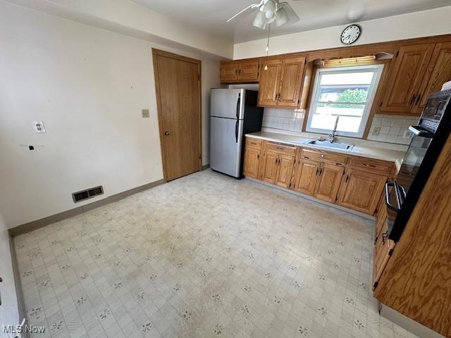 8375 Royal Ridge Dr, Parma, OH 44129 - kitchen with freestanding refrigerator, light countertops, brown cabinets, a ceiling fan, and light flooring