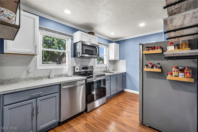 21100 Watson Rd, Maple Heights, OH 44137 - kitchen with stainless steel appliances, ornamental molding, open shelves, backsplash, and light wood finished floors