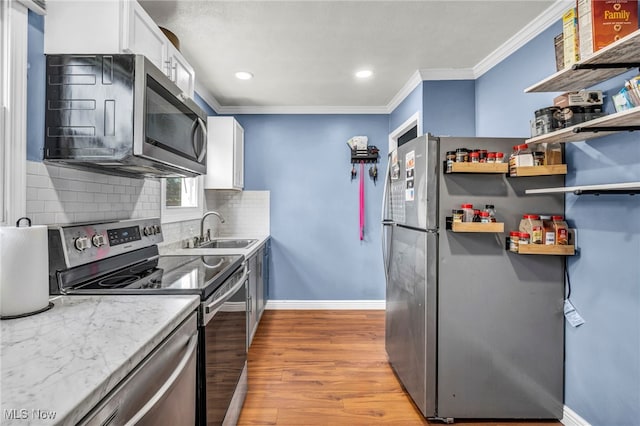 21100 Watson Rd, Maple Heights, OH 44137 - kitchen featuring stainless steel appliances, crown molding, decorative backsplash, white cabinets, and light wood-style flooring