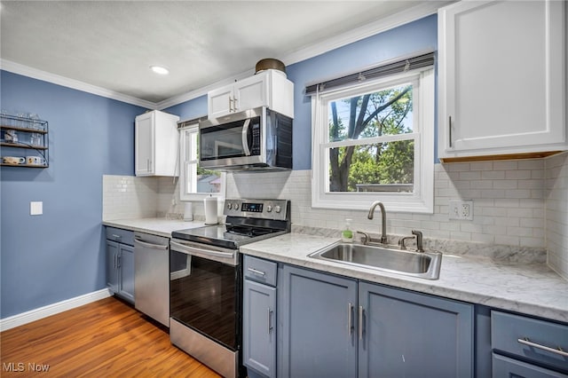 21100 Watson Rd, Maple Heights, OH 44137 - kitchen with appliances with stainless steel finishes, crown molding, tasteful backsplash, wood finished floors, and white cabinetry