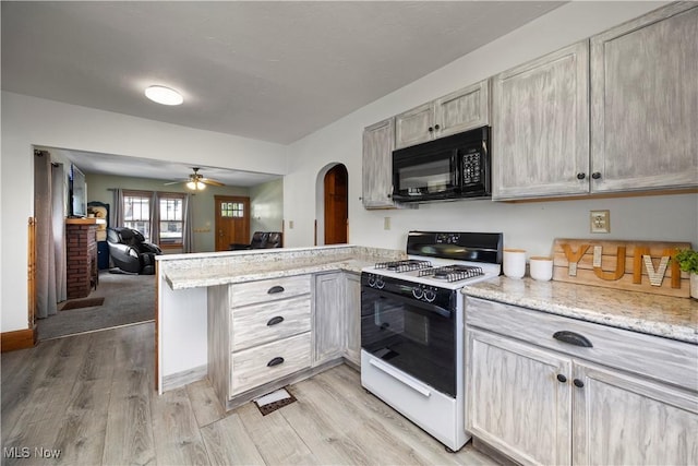1029 S Main St, Grafton, OH 44044 - kitchen featuring range with gas stovetop, black microwave, a peninsula, arched walkways, and light wood finished floors