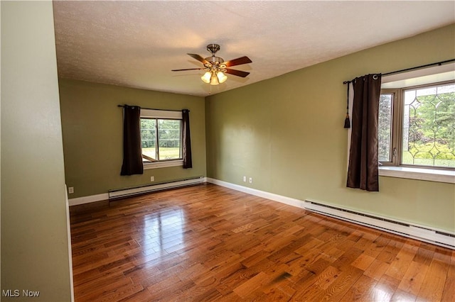 9306 Beech St, Louisville, OH 44641 - unfurnished room with a baseboard radiator, plenty of natural light, wood finished floors, and a textured ceiling
