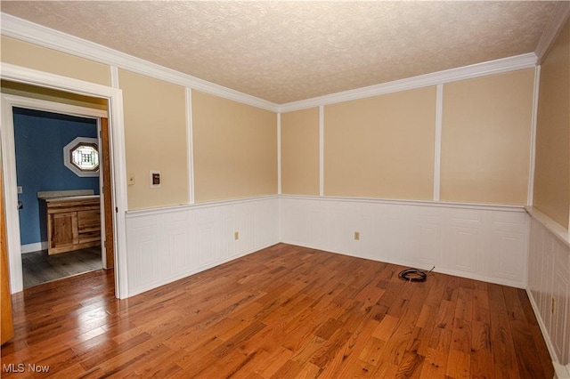 9306 Beech St, Louisville, OH 44641 - unfurnished room featuring wood finished floors, a decorative wall, a textured ceiling, and a wainscoted wall