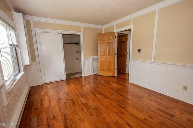 9306 Beech St, Louisville, OH 44641 - unfurnished bedroom featuring light wood-style flooring, a decorative wall, a closet, a wainscoted wall, and a baseboard radiator