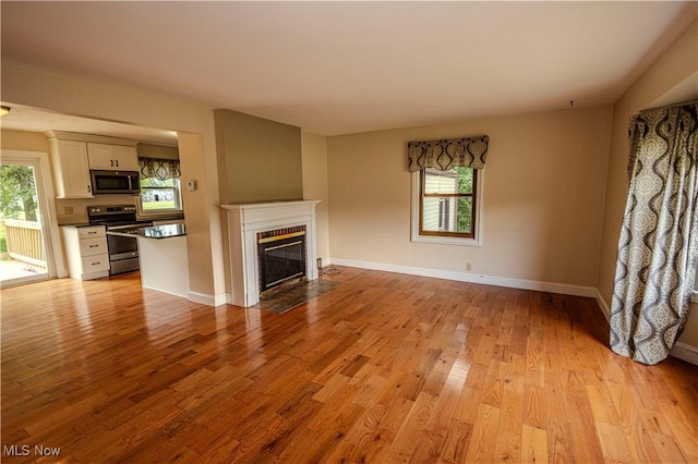 9306 Beech St, Louisville, OH 44641 - unfurnished living room featuring healthy amount of natural light, wood finished floors, and a fireplace with flush hearth