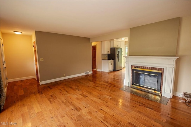 9306 Beech St, Louisville, OH 44641 - unfurnished living room featuring light wood-style floors and a brick fireplace